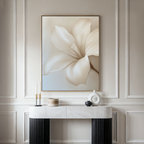 A minimalist console table with black legs and a white marble top displays candles and vases beneath the Pure Magnolia Canvas Art—a striking focal point for elegant bedroom decor.