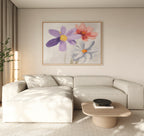 A modern living room features a light beige sectional, light wood coffee table, potted plant, and the Blooming Harmony Canvas Art - Horizontal with three colorful flowers on white. Neutral tones and soft natural lighting create a serene space.