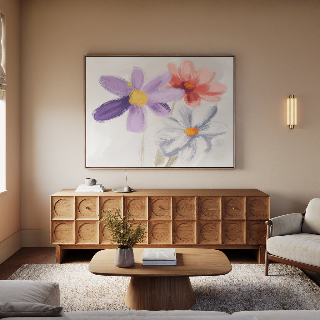 A cozy living room with a modern wooden sideboard, light sofa, wooden coffee table, beige rug, and the Blooming Harmony Canvas Art - Horizontal featuring purple, red, and white flowers hanging above the sideboard.