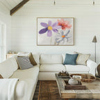 A bright, cozy living room with white shiplap walls, a large L-shaped white sofa, rustic wooden coffee table, and the "Blooming Harmony Canvas Art - Horizontal" featuring purple, pink, and white flowers on the wall.