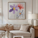 A cozy living room with a beige sofa, cushions, a light wood side table with lamp, dried flowers in a vase, and the Blooming Harmony Canvas Art - Square featuring three colorful flowers displayed above the sofa.