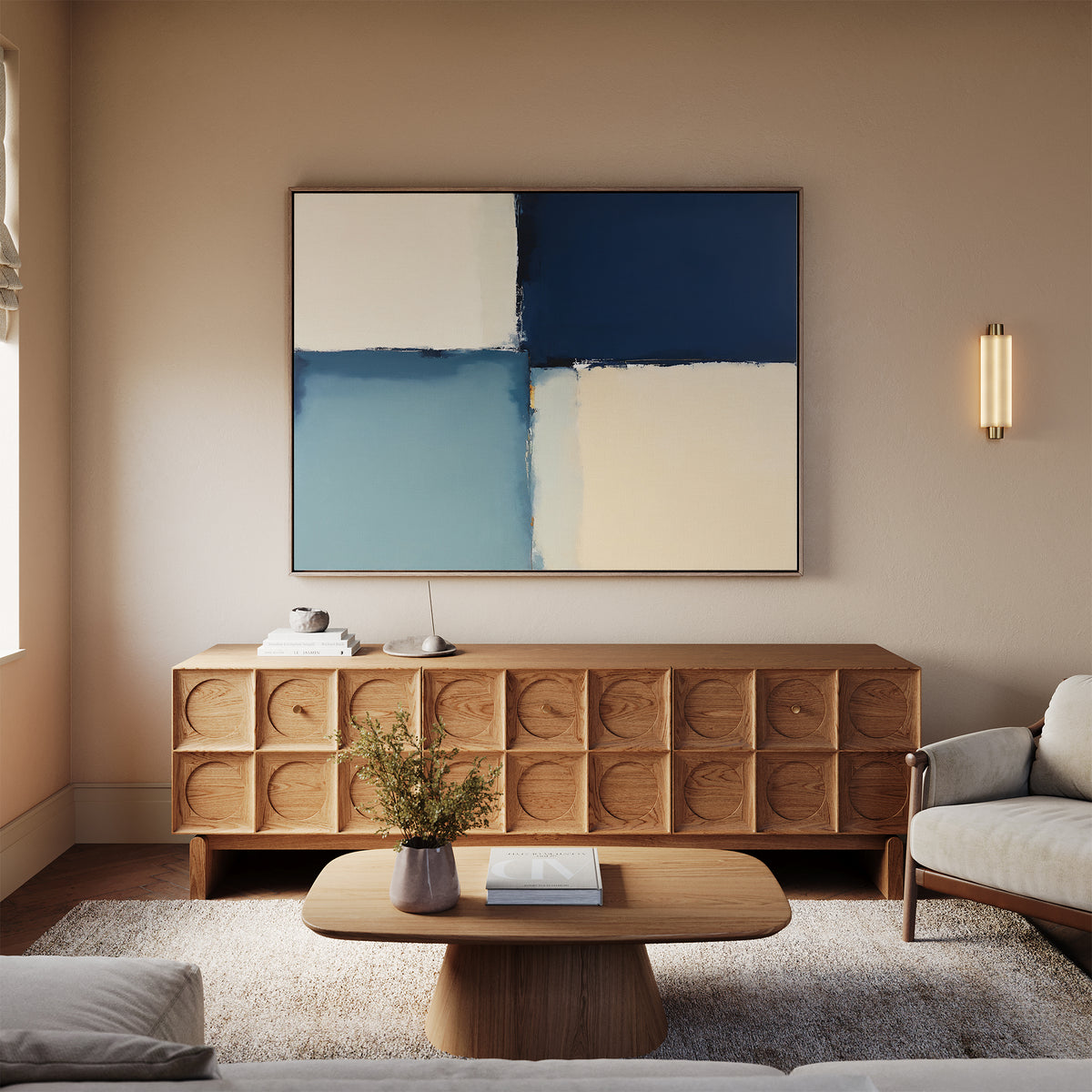 A modern living room with a light sofa, wooden coffee table, textured sideboard, and the Blue Quarters Canvas Art - Horizontal in blue and cream on the wall. A soft beige rug covers the floor, with a small vase of flowers on the table.