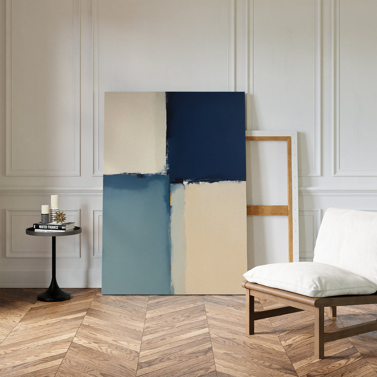 A modern room with herringbone wood floors displays the Blue Quarters Canvas Art - Vertical in blue and beige tones against a white-paneled wall, near a cushioned chair and a small round table with candles and books.