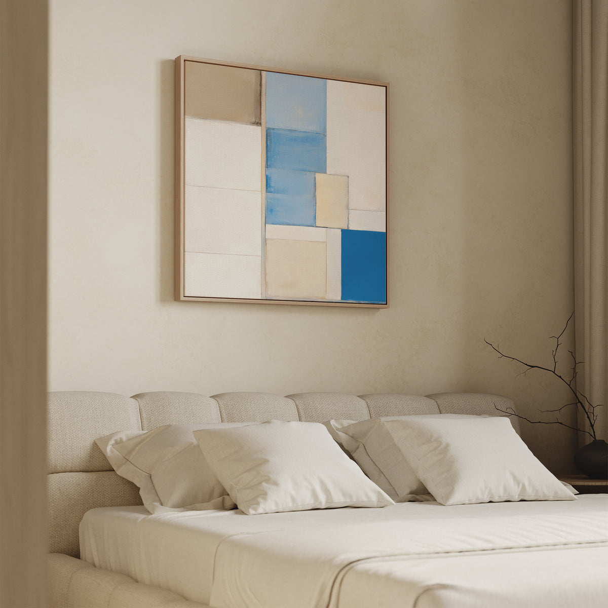 A neatly made bed with white sheets sits against a beige wall, topped by the Blue Tiles Composition Canvas Art - Square in blue, beige, and white. A bare branch on the nightstand adds a modern living room decor touch.