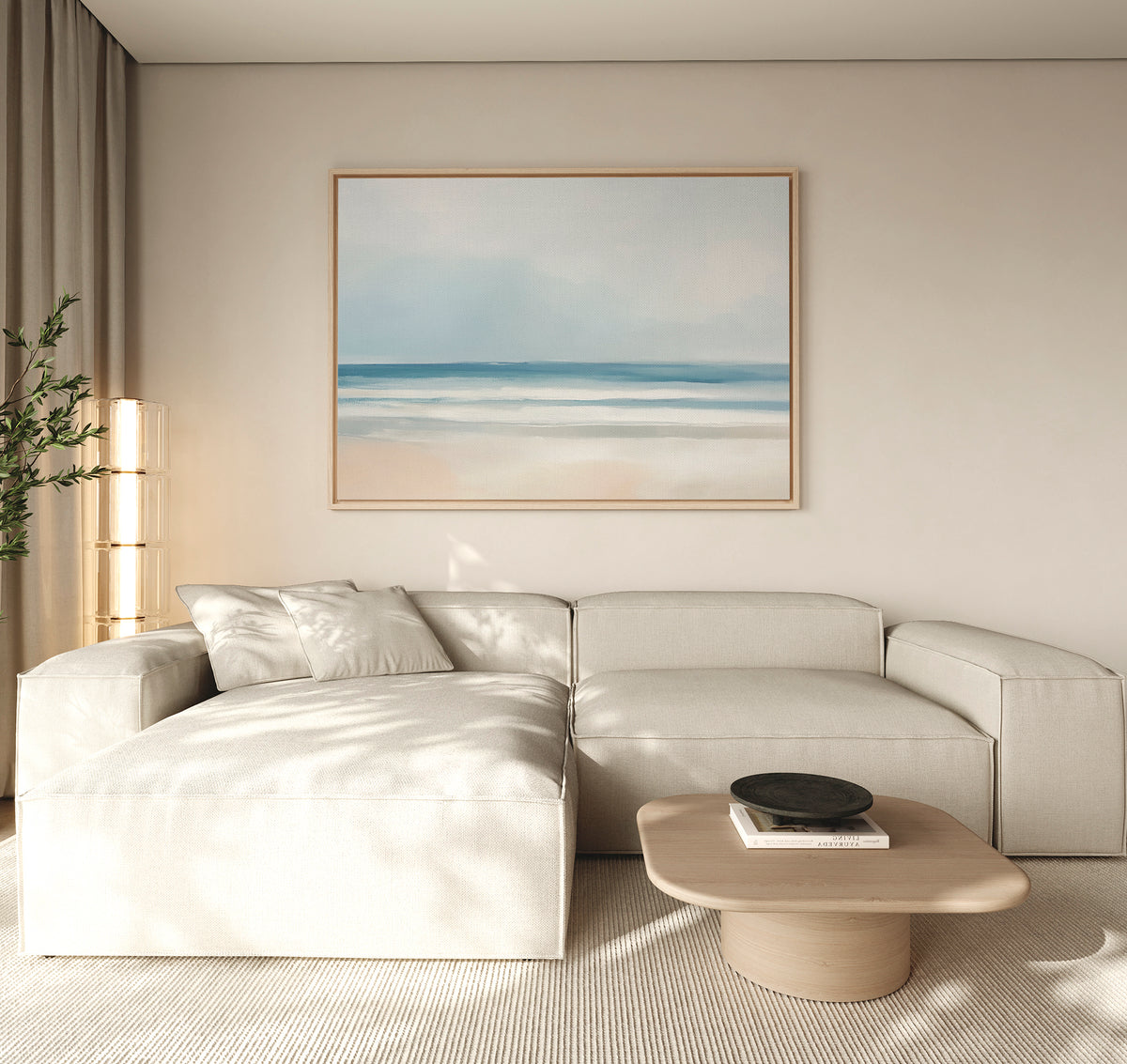A modern living room with a light beige sectional, low wooden coffee table topped with a black bowl, "Blurred Beach Scene Canvas Art - Horizontal" on the wall, soft natural light, and a plant in the corner.