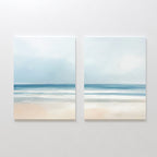The Blurred Beach Scene - Set Of 2 features minimalist beach wall art with soft blue sky, gentle waves, and a sandy shore, displayed side by side for calming and serene decor.