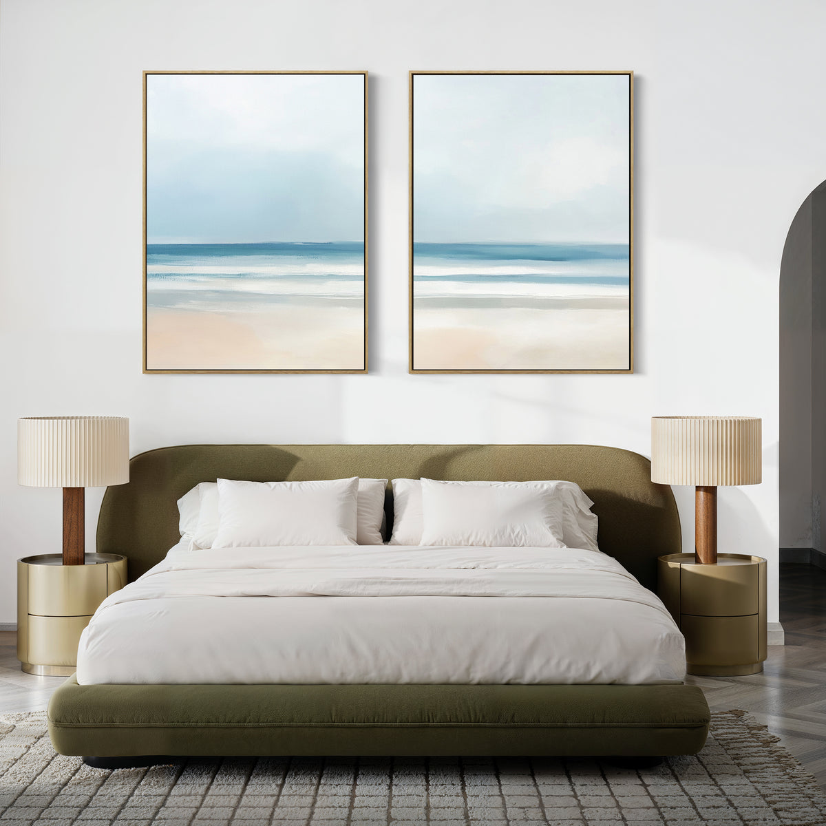 A modern bedroom features a low olive-green bed with white bedding, gold nightstands, beige lamps, and the Blurred Beach Scene - Set Of 2 artwork above the bed for a serene, coastal-inspired decor.