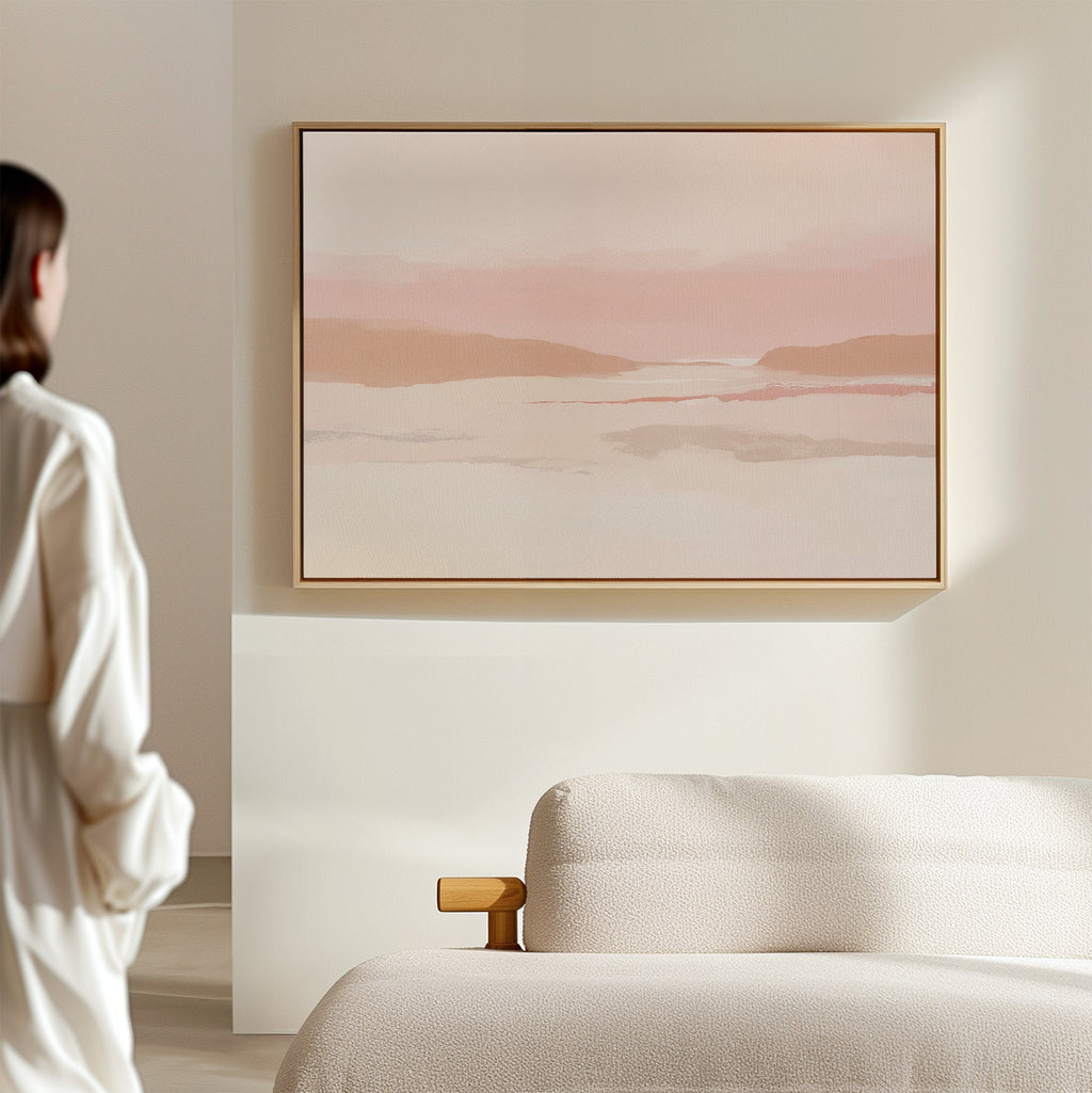 A person stands in a minimalist room facing the Blush Mesa Canvas Art - Horizontal above a cream sofa, creating an inviting earth-toned decor.