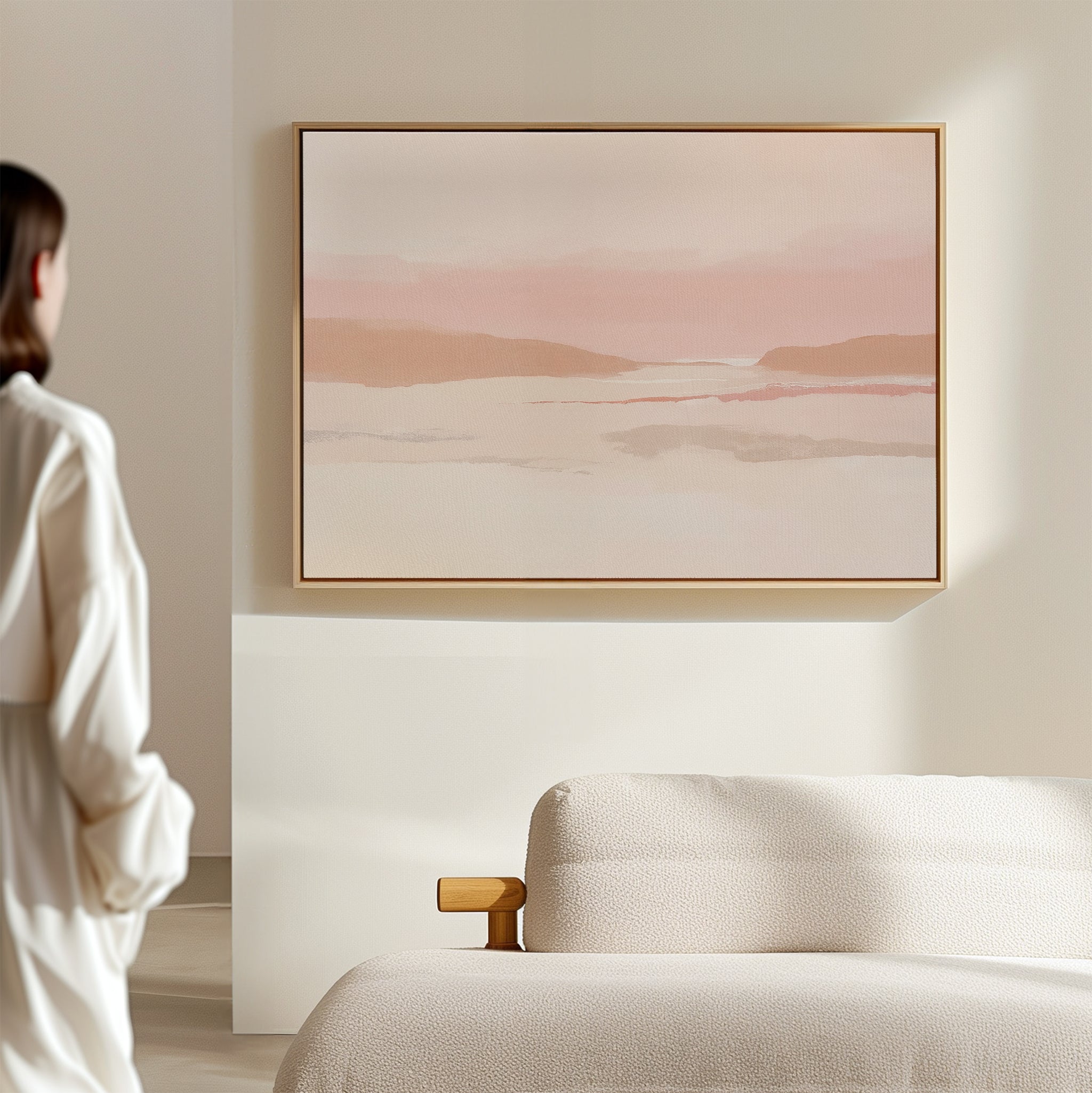 A person stands in a minimalist room facing the Blush Mesa Canvas Art - Horizontal above a cream sofa, creating an inviting earth-toned decor.