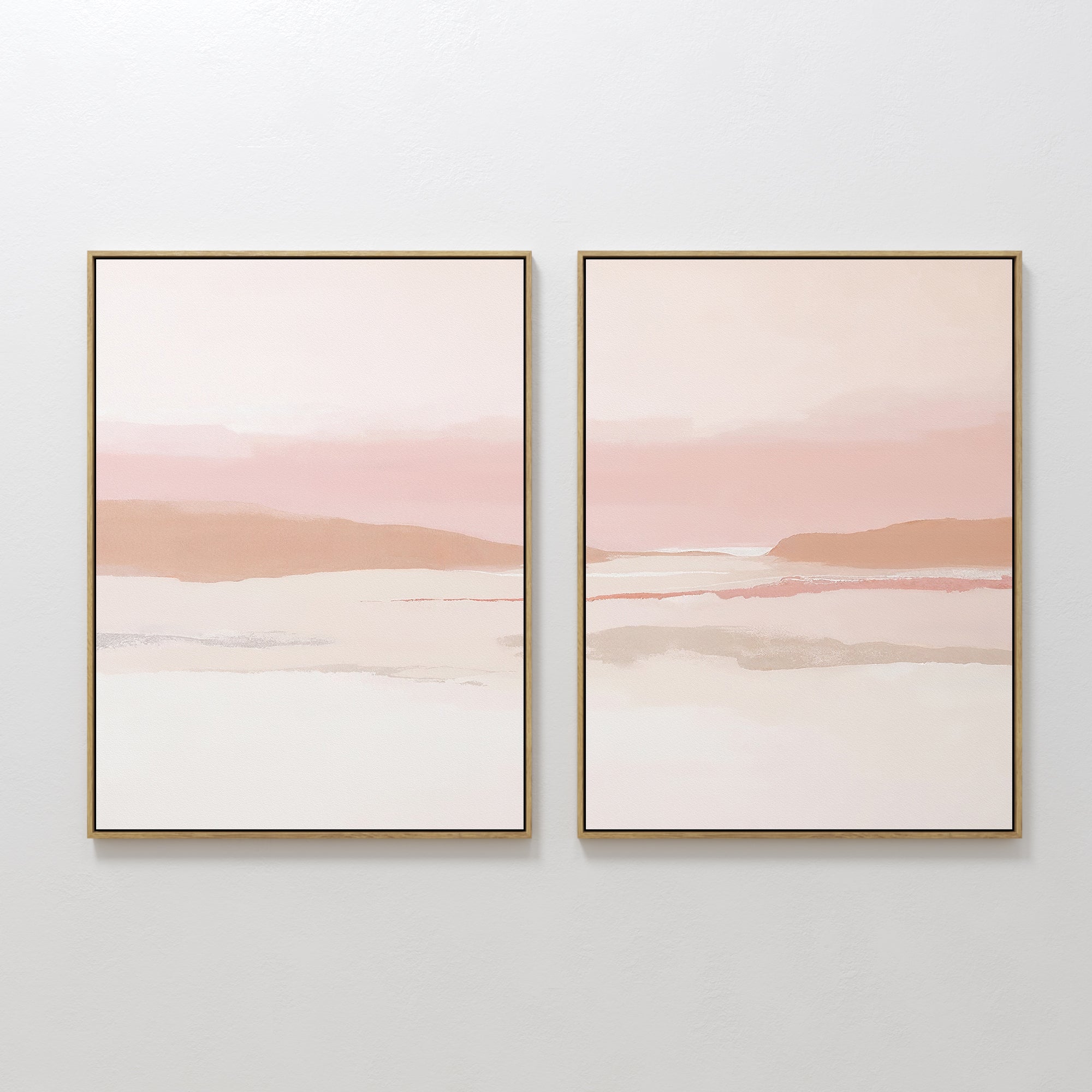 The Blush Mesa - Set Of 2 features framed abstract landscape prints in soft pastel pink, beige, and white tones, adding serene minimalist style to a light-colored wall.