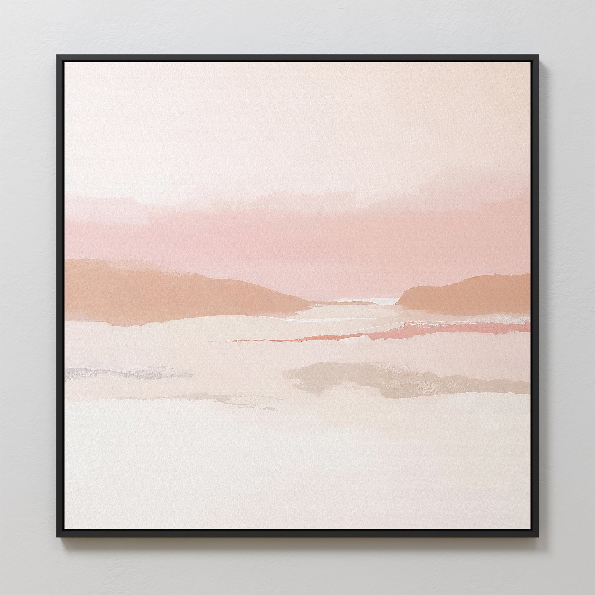 The Blush Mesa Canvas Art - Square is a minimalist wall piece featuring soft pastel earth tones of pink, peach, and beige in abstract hills under a calm sky, framed in black and displayed on a light-colored wall.