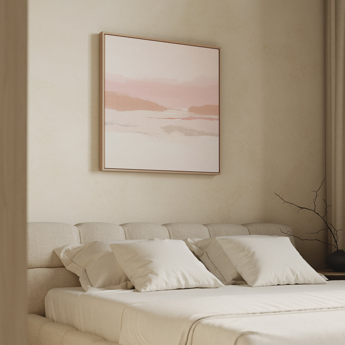 A minimalist bedroom features a beige upholstered bed with white bedding and pillows. Above, the Blush Mesa Canvas Art - Square in soft pink and cream tones is framed. A bare branch sits on the nightstand for decor.