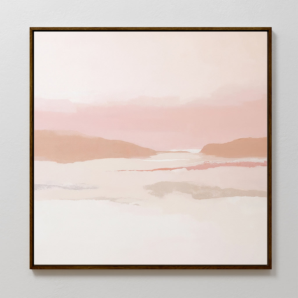 The Blush Mesa Canvas Art - Square features an abstract landscape in soft pink, beige, and white tones with distant hills and a calm sky, set in a sleek dark wooden frame—ideal for bringing tranquility to any space.