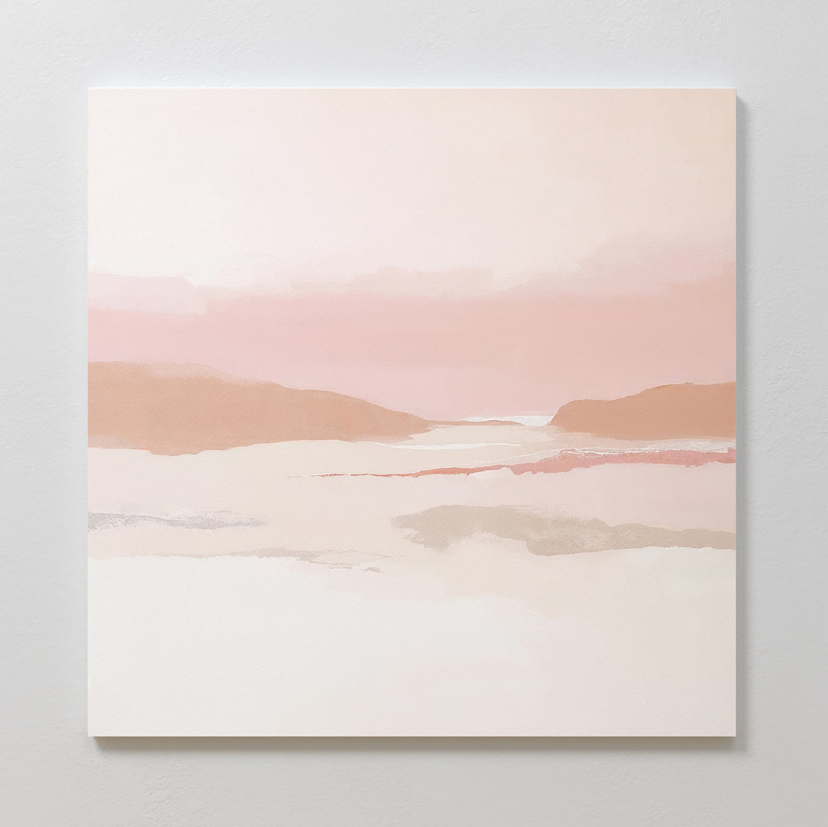 The Blush Mesa Canvas Art - Square showcases minimalist wall art in soft pink and beige earth tones, with gentle hills and a hazy sky, beautifully displayed on a light-colored wall.