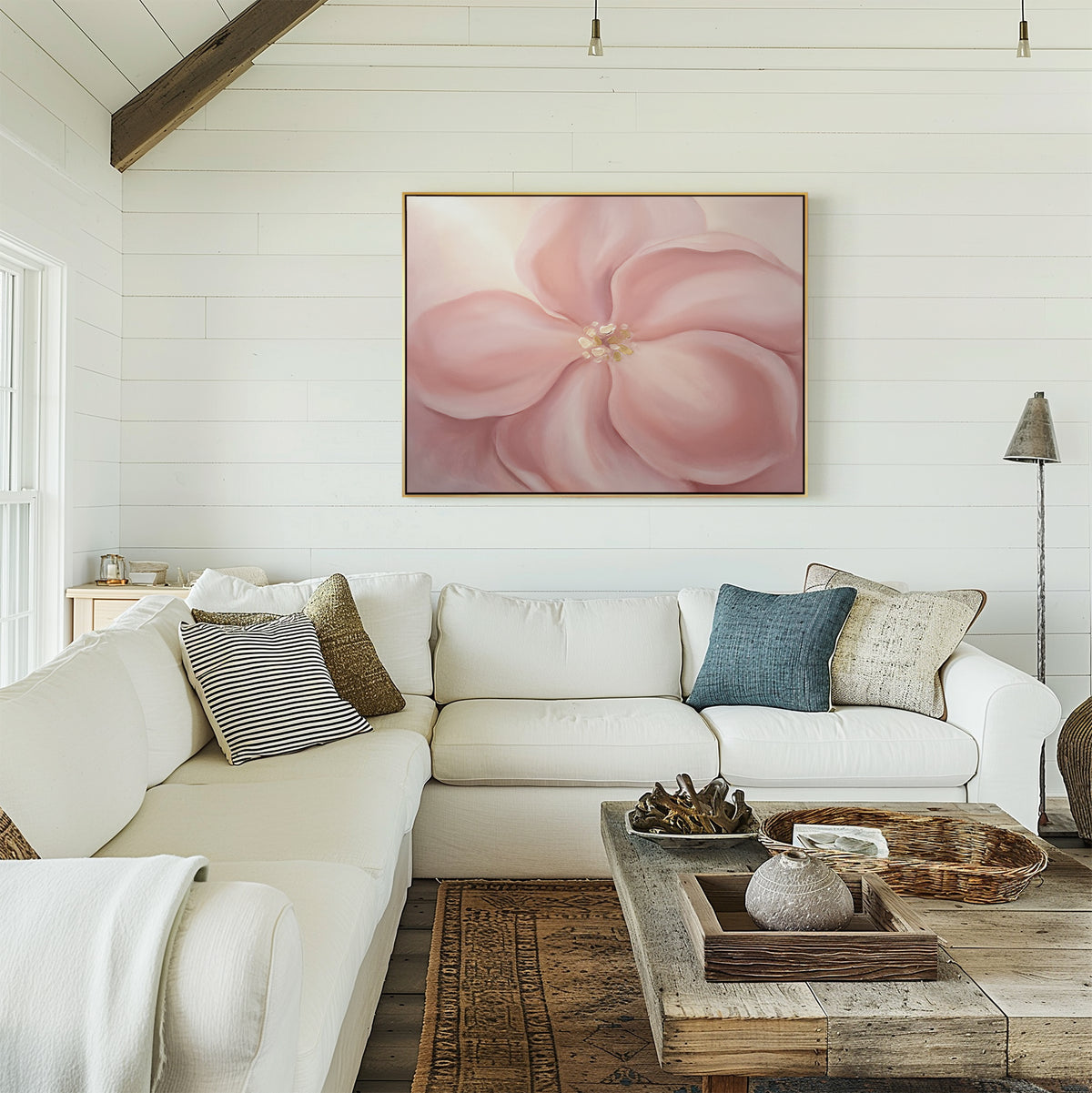 A bright, cozy living room with white walls, a large white sectional with cushions, a rustic wooden coffee table, and the Blushing Magnolia Canvas Art - Horizontal above the sofa for soft romantic wall décor.