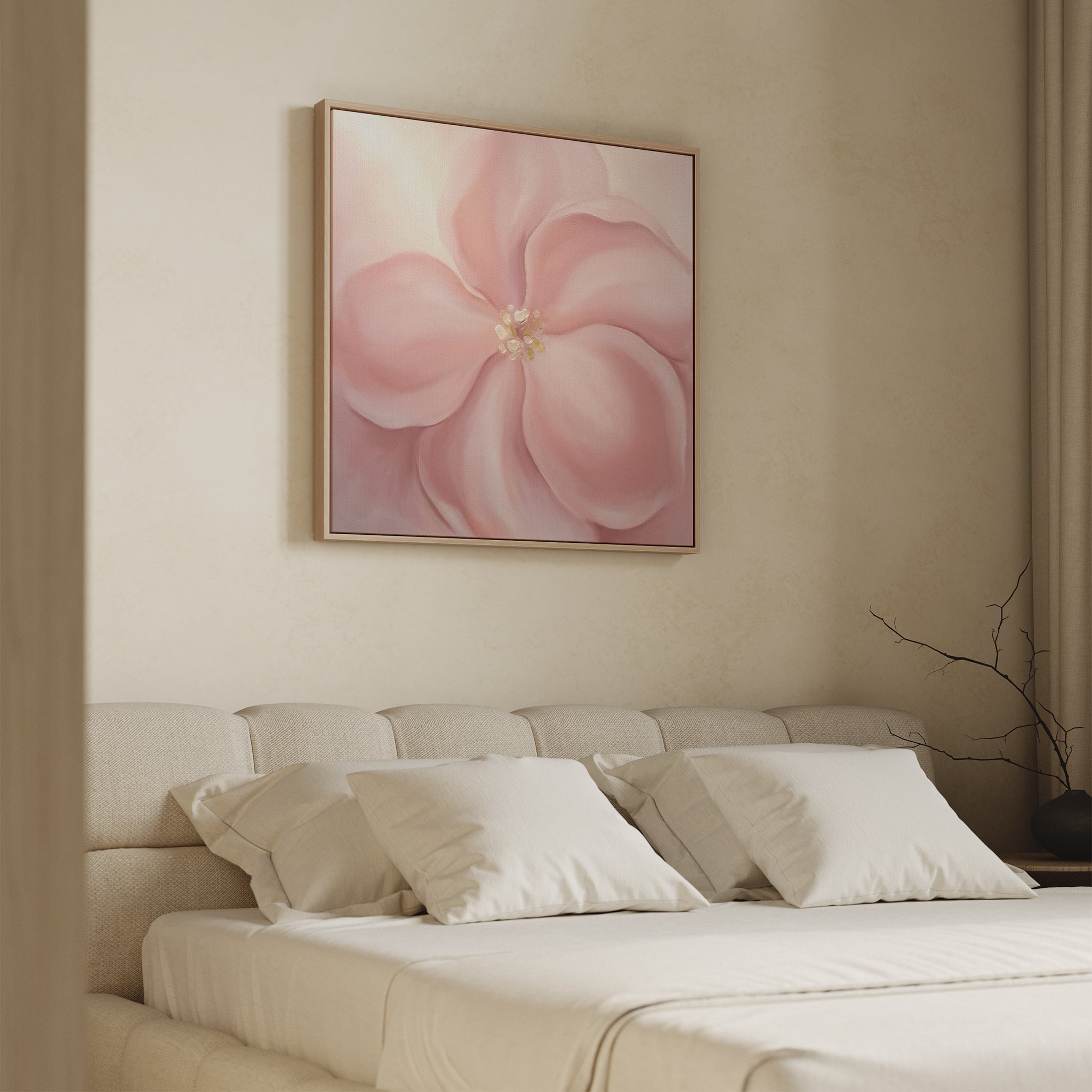 A neutral-toned bedroom showcases a beige upholstered bed, white pillows, and the Blushing Magnolia Canvas Art - Square above the headboard. Soft natural light fills the space, with a bare branch adding elegance to the bedside table.
