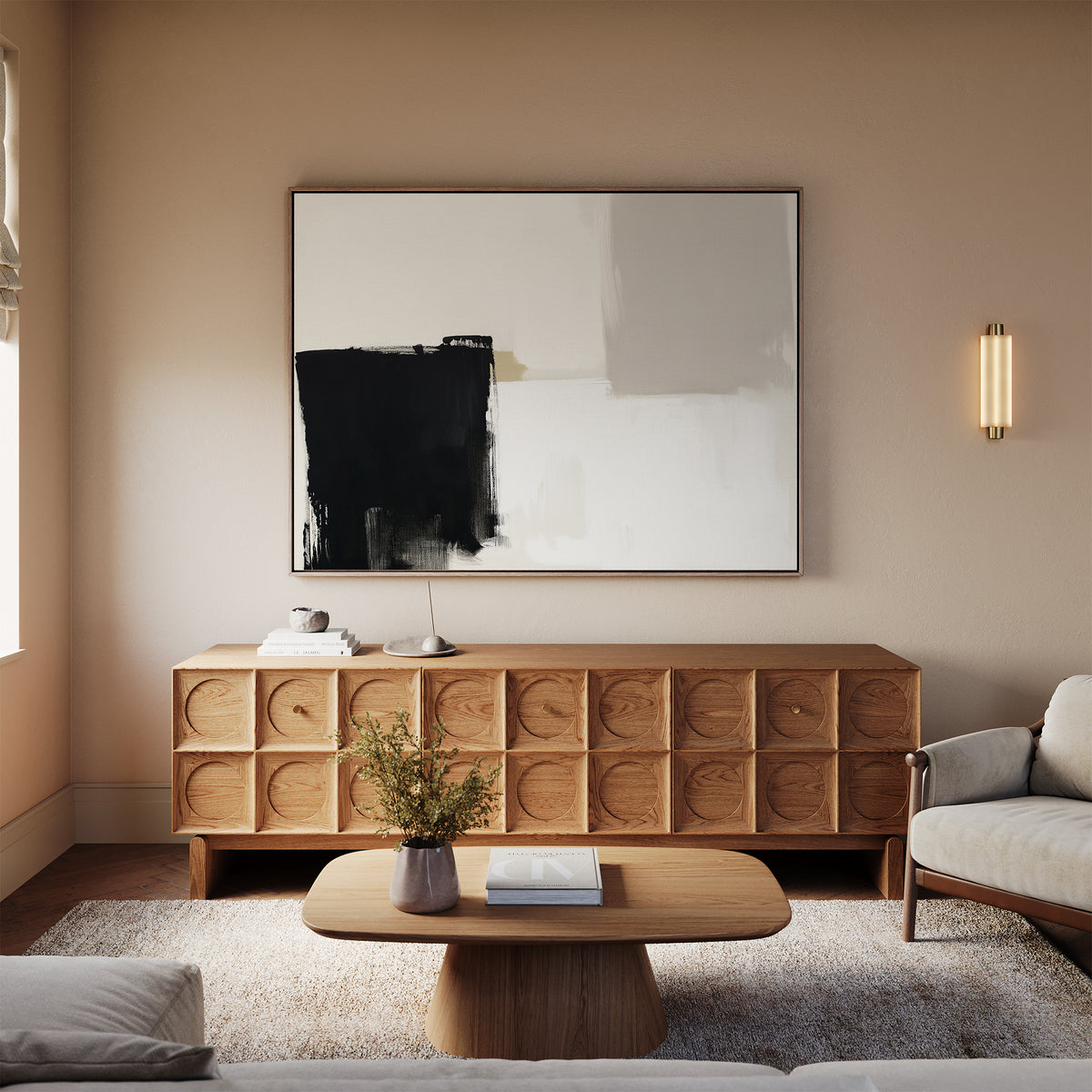 A modern living room with a light sofa, wooden coffee table, textured wooden sideboard, and beige walls showcases the Bold Division Canvas Art - Horizontal as an abstract black and white print. A wall sconce and a vase with flowers complete the look.