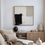 A modern living room featuring a beige couch, neutral cushions, a wooden sideboard with vases and books, and the Bold Division Canvas Art - Square inspired by Nordic Park artwork displayed on a white wall.