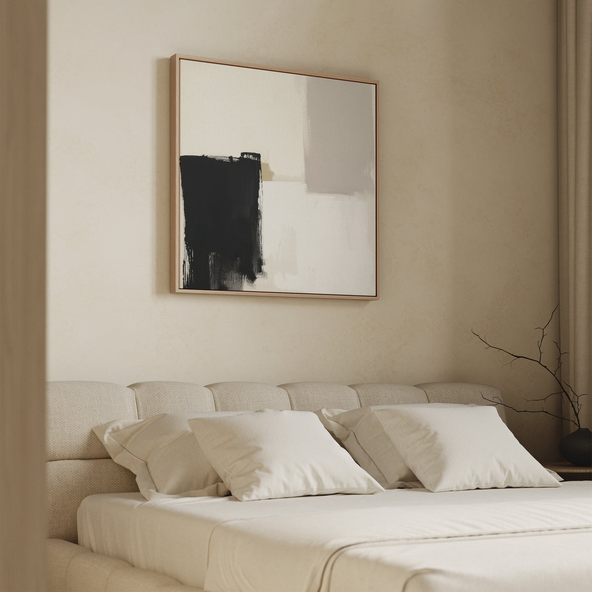 A minimalist bedroom features a beige upholstered bed with four cream pillows, and the Bold Division Canvas Art - Square in black and white above the headboard. A branch in a vase decorates the bedside table.