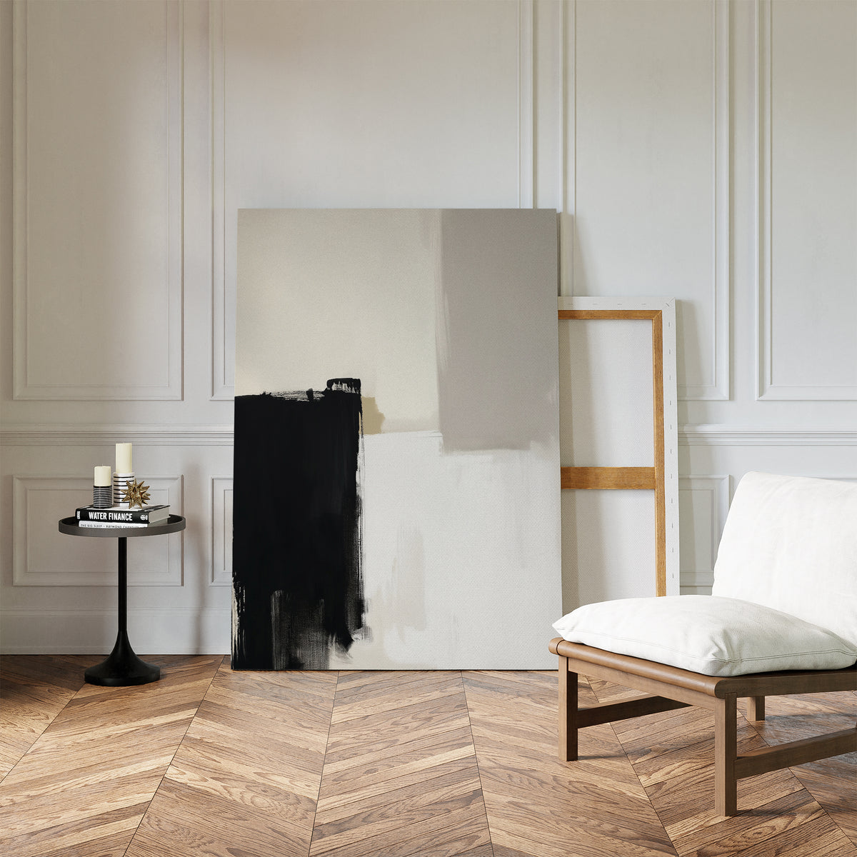 Minimalist interior with herringbone wood floor, a white cushioned chair, side table, and candles—perfect for modern living rooms. Two large canvases, including the Bold Division Canvas Art - Vertical, lean against the white paneled wall.