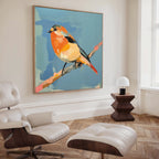 A modern living room with a leather lounge chair and ottoman, a geometric wooden side table with a lamp, and the Bright Songbird Canvas Art - Square adds vibrant character with its colorful bird on a branch.