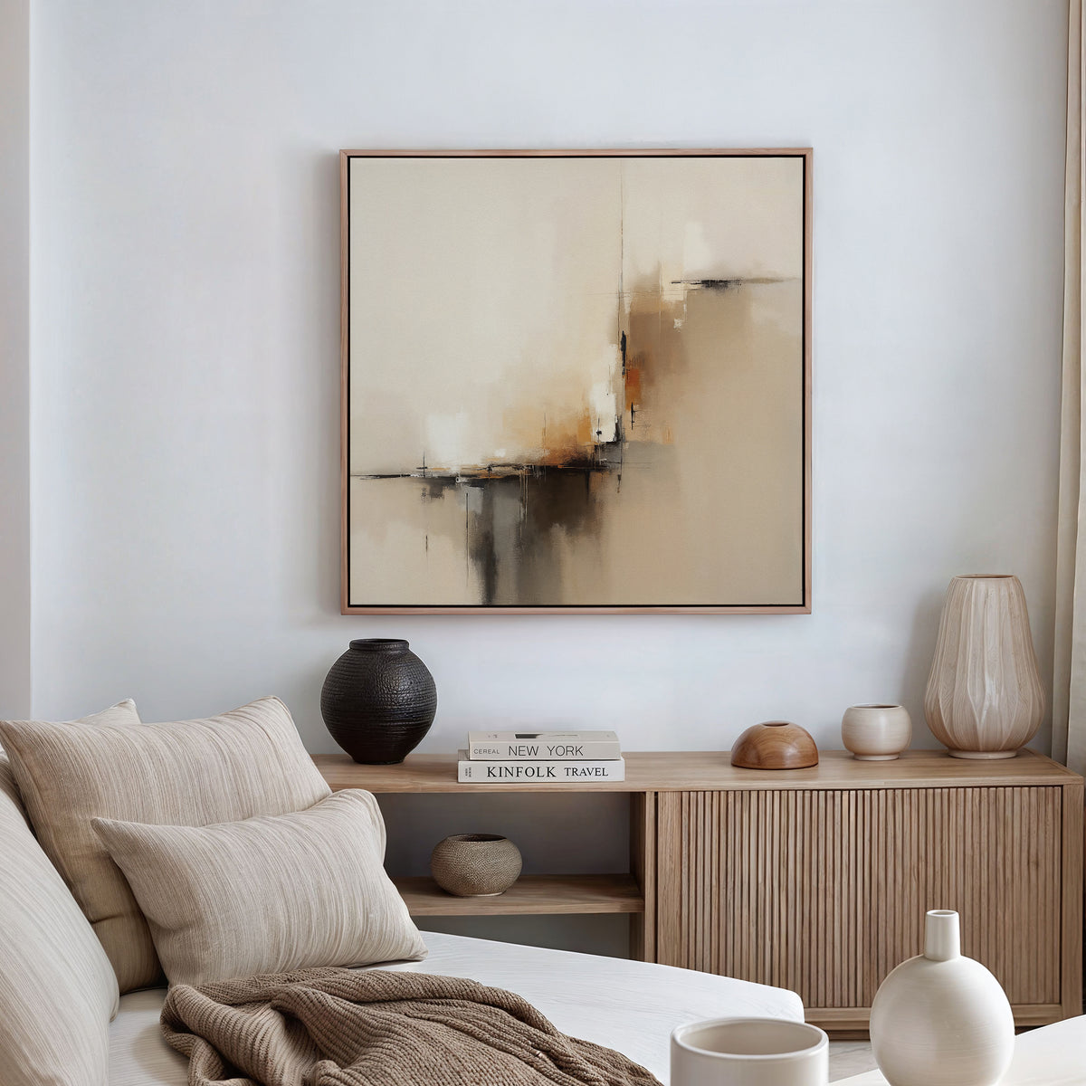 A modern living room with a beige sofa, neutral pillows, wooden sideboard, and decorative vases and books. The Burnt Sienna Convergence Canvas Art - Square adds a calming, contemporary touch for a cozy Nordic Park-inspired vibe.