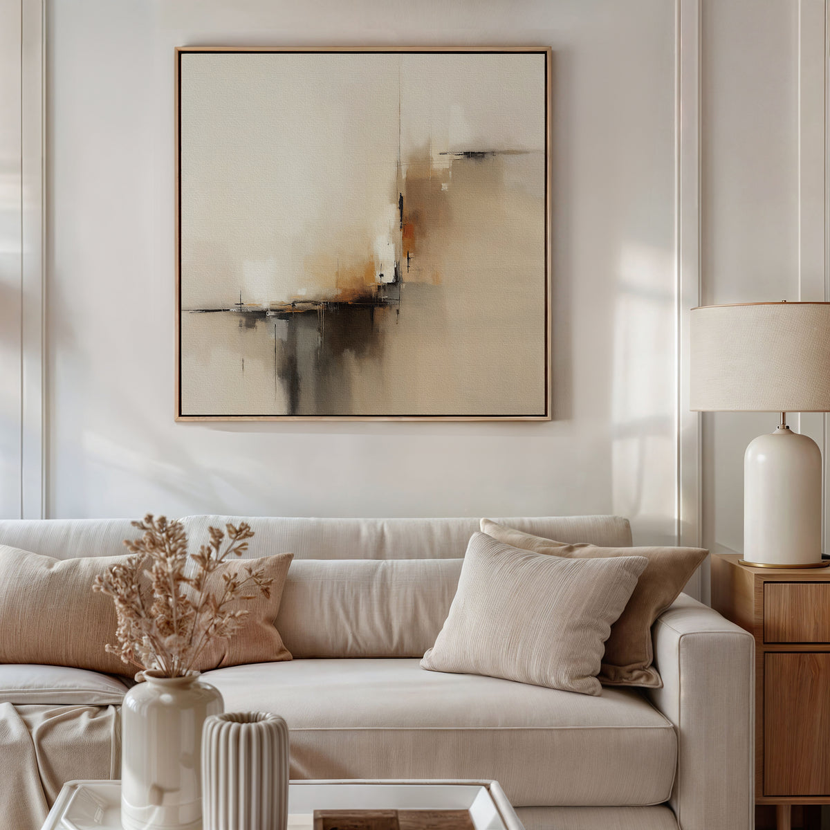 A modern living room features a beige sofa, matching cushions, a side table with a white lamp, dried flowers in a vase, and the Burnt Sienna Convergence Canvas Art - Square—perfect for achieving that Nordic Park-inspired ambiance.