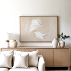 A minimalist living room features the Garden Spectrum Abstract Canvas Art above a white sofa with plush cushions, complemented by a light wood sideboard, neutral vases, a lamp, and greenery—a serene touch to your decor.