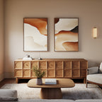 A modern living room featuring a geometric wooden sideboard, low wooden coffee table, light gray sofa, and Canyon Curves - Set Of 2 wall art in earthy tones above the sideboard. A small vase with greenery sits on the table.