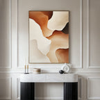 A minimalist console table with decorative objects sits against a paneled wall, topped by the Canyon Curves Canvas Art - Vertical in warm beige, brown, and cream—an ideal accent for modern living rooms.