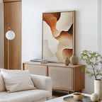 A modern, minimalist living room features a light wood sideboard with neutral vases, books, and the Canyon Curves Canvas Art - Vertical in warm earth tones. A white sofa, round lamp, and potted plant complete the airy, serene decor.