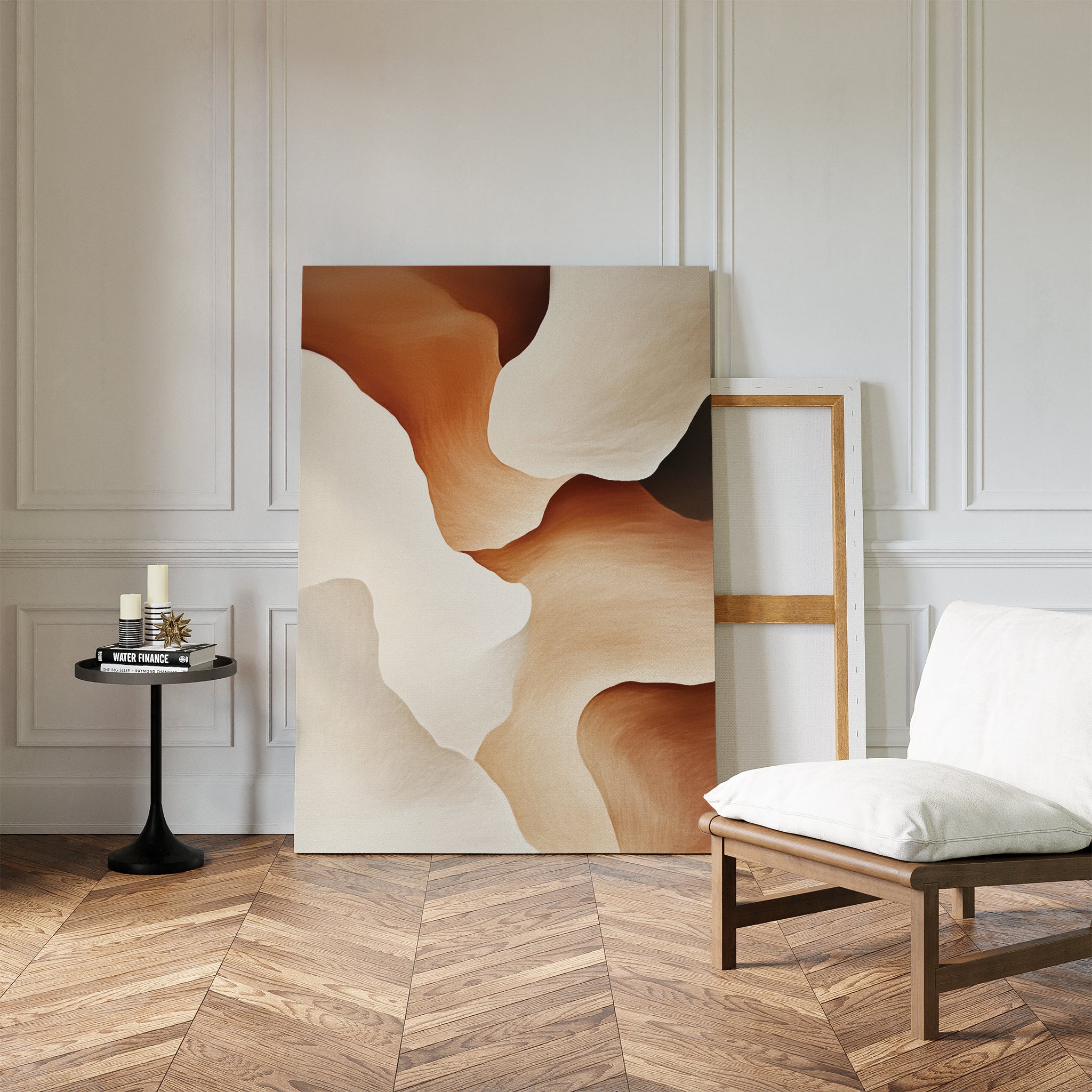 A minimalist room with herringbone wood floors, a white cushioned chair, a round black table with candles, and the Canyon Curves Canvas Art - Vertical in beige and brown tones leaning against a white paneled wall—ideal for modern spaces.