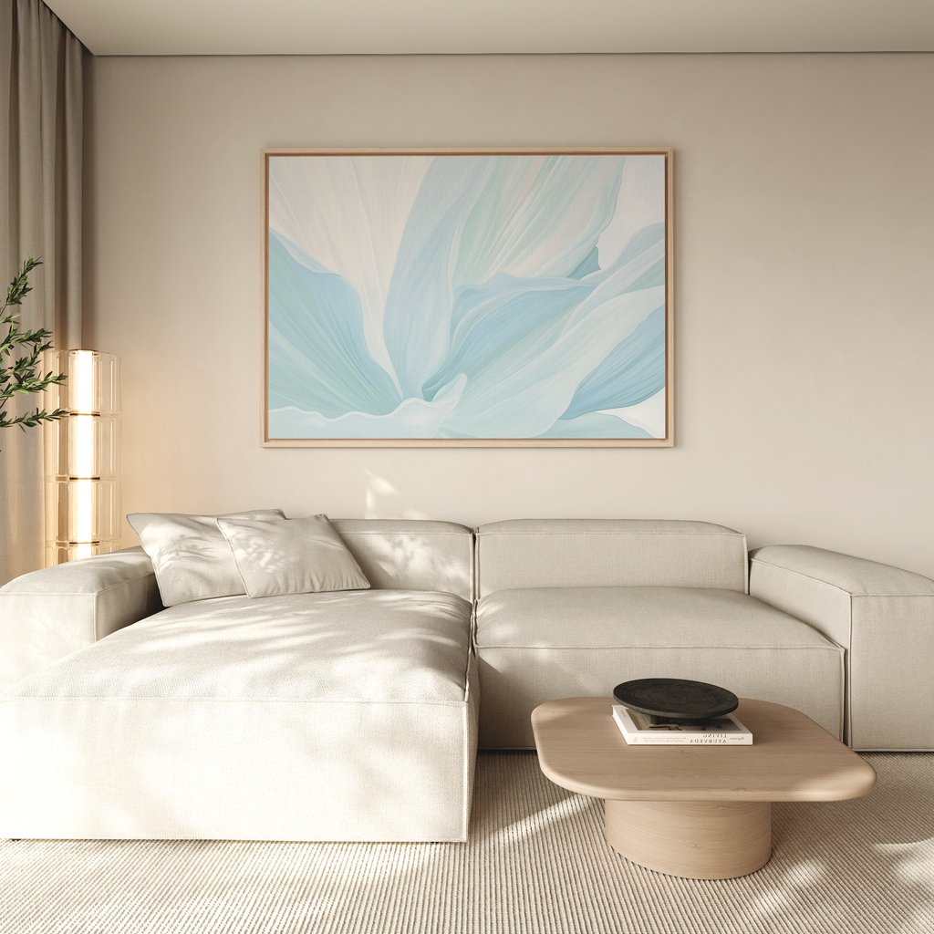 A modern living room with a light beige sectional sofa and neutral walls features the Icy Petals Abstract Canvas Art in blue and white above. A wooden coffee table holds books and a black bowl, while sunlight filters through sheer curtains.