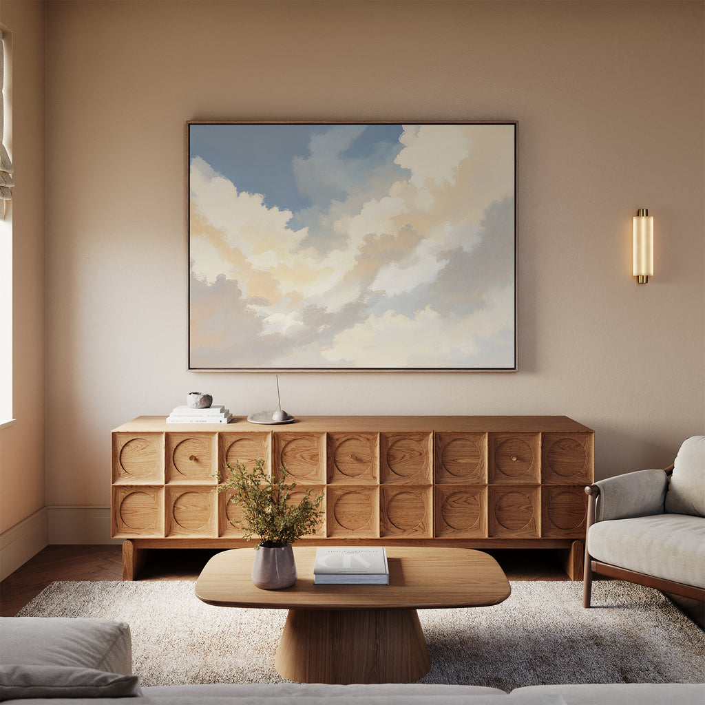 A cozy living room with neutral tones features a geometric wooden sideboard, the Celestial Embrace Canvas Art - Horizontal as wall decor, a light wood coffee table, white sofa, wall sconce above, and a plush rug.