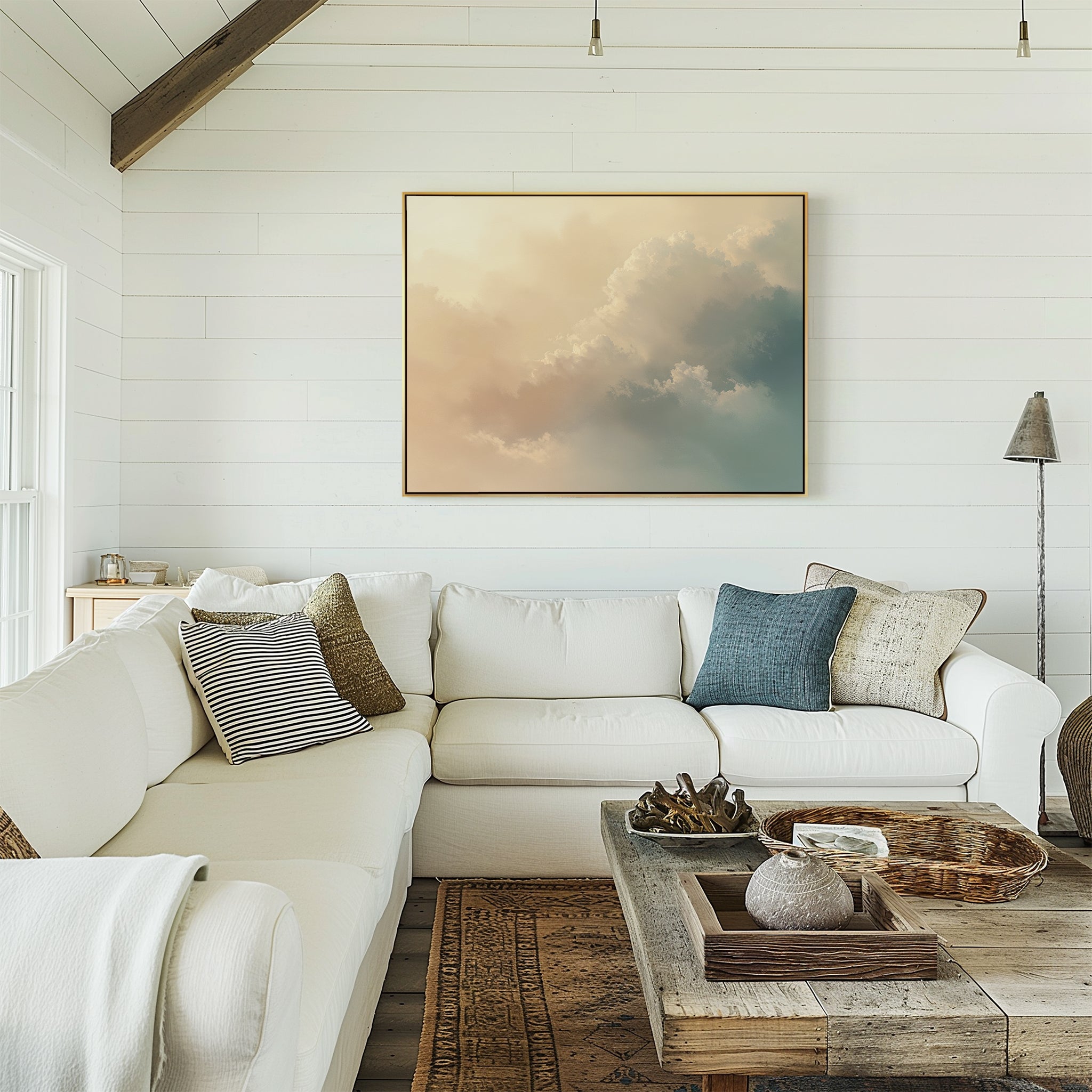 A cozy living room features white shiplap walls, a large white sectional with assorted pillows, a rustic wooden coffee table, and the Celestial Veil Canvas Art - Horizontal basking in gentle champagne light above the couch.
