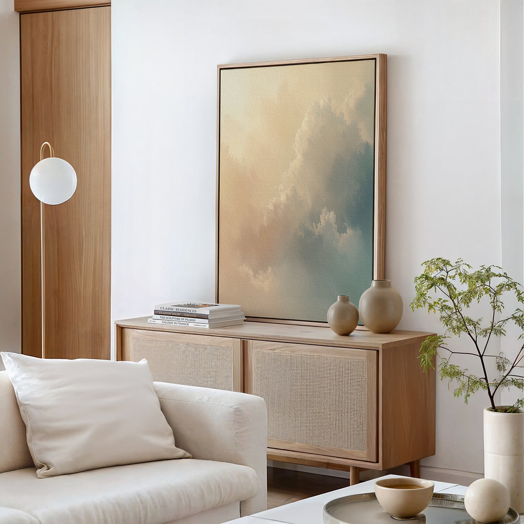 A minimal living room features a light wood sideboard, neutral ceramics, a small plant, a white armchair with a cushion, and the Celestial Veil Canvas Art - Vertical. Calm modern decor in soft neutrals is bathed in champagne light.