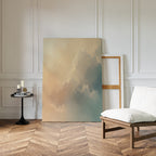 A cozy, minimalistic room with a wooden herringbone floor, white padded chair, and round black side table with candles in soft champagne light. The Celestial Veil Canvas Art - Vertical leans against the white paneled wall.