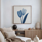 A modern living room features a beige sofa, neutral cushions, and wooden sideboard. The Cerulean Tulips Canvas Art - Square hangs above, while decorative vases and books complete the Nordic Park-inspired decor.