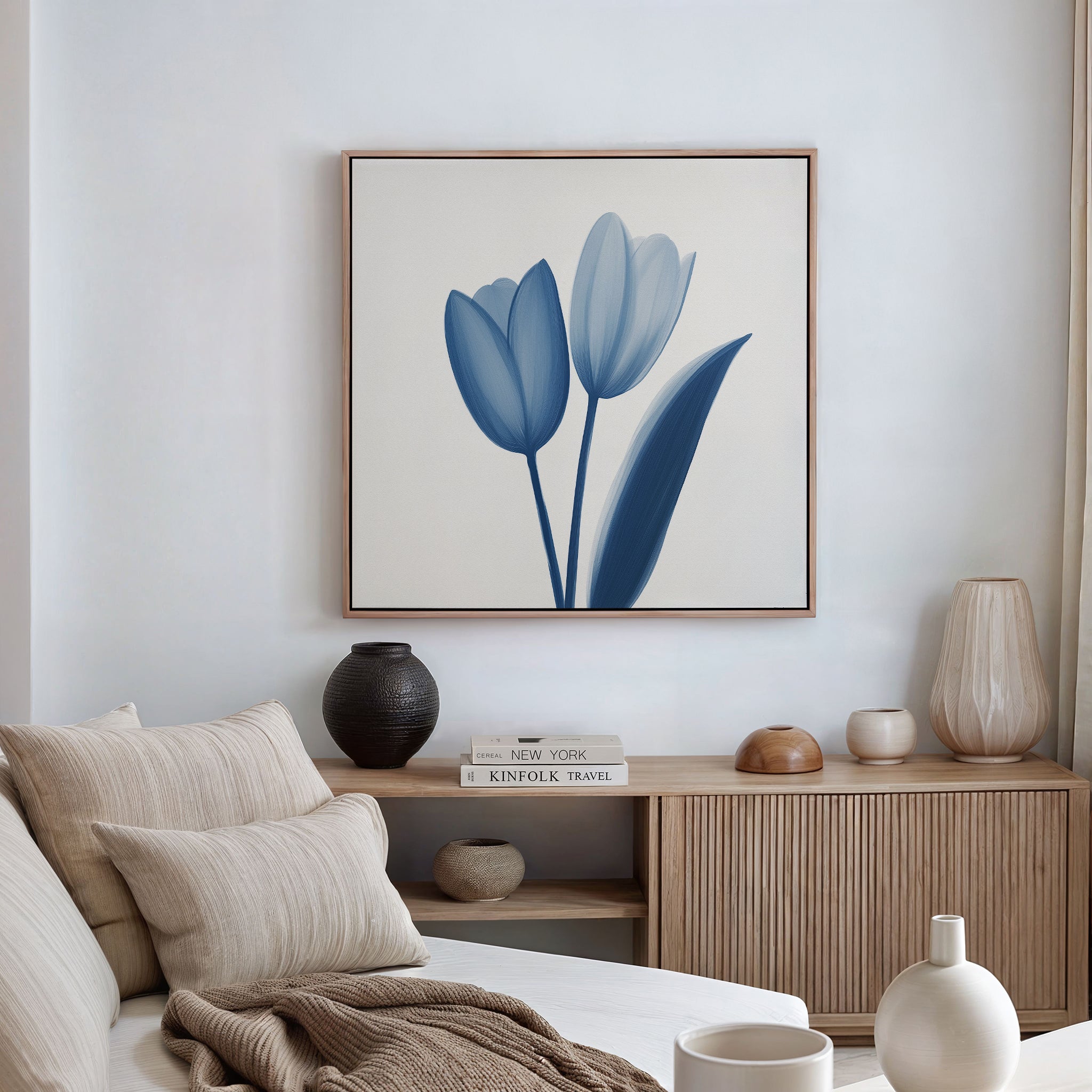 A modern living room features a beige sofa, neutral cushions, and wooden sideboard. The Cerulean Tulips Canvas Art - Square hangs above, while decorative vases and books complete the Nordic Park-inspired decor.