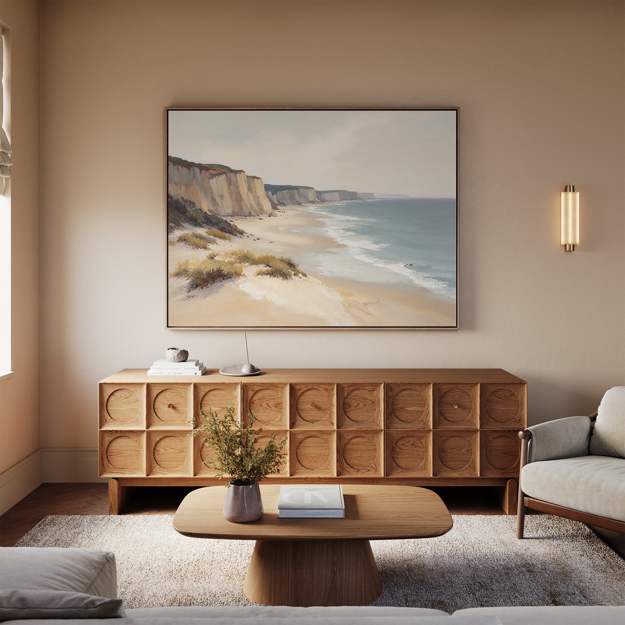 A cozy living room with neutral tones features a light sofa, wooden coffee table with a vase, patterned sideboard, and the Chalk Shores Canvas Art - Horizontal hanging above the sideboard for a seaside decor touch.