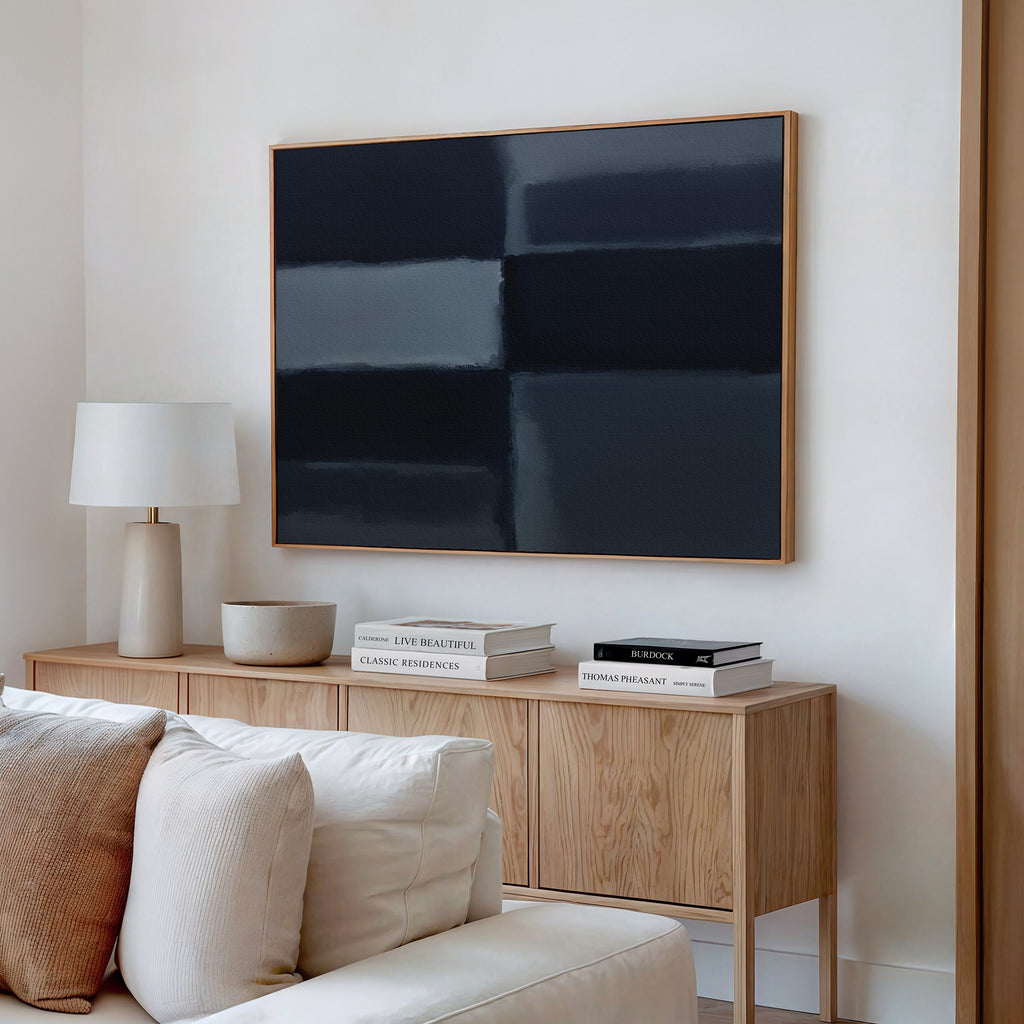 A modern living room featuring a light wood sideboard, white table lamp, stacked books, decorative bowls, cream sofa, and the Charcoal Blocks Canvas Art - Horizontal as striking geometric wall decor.