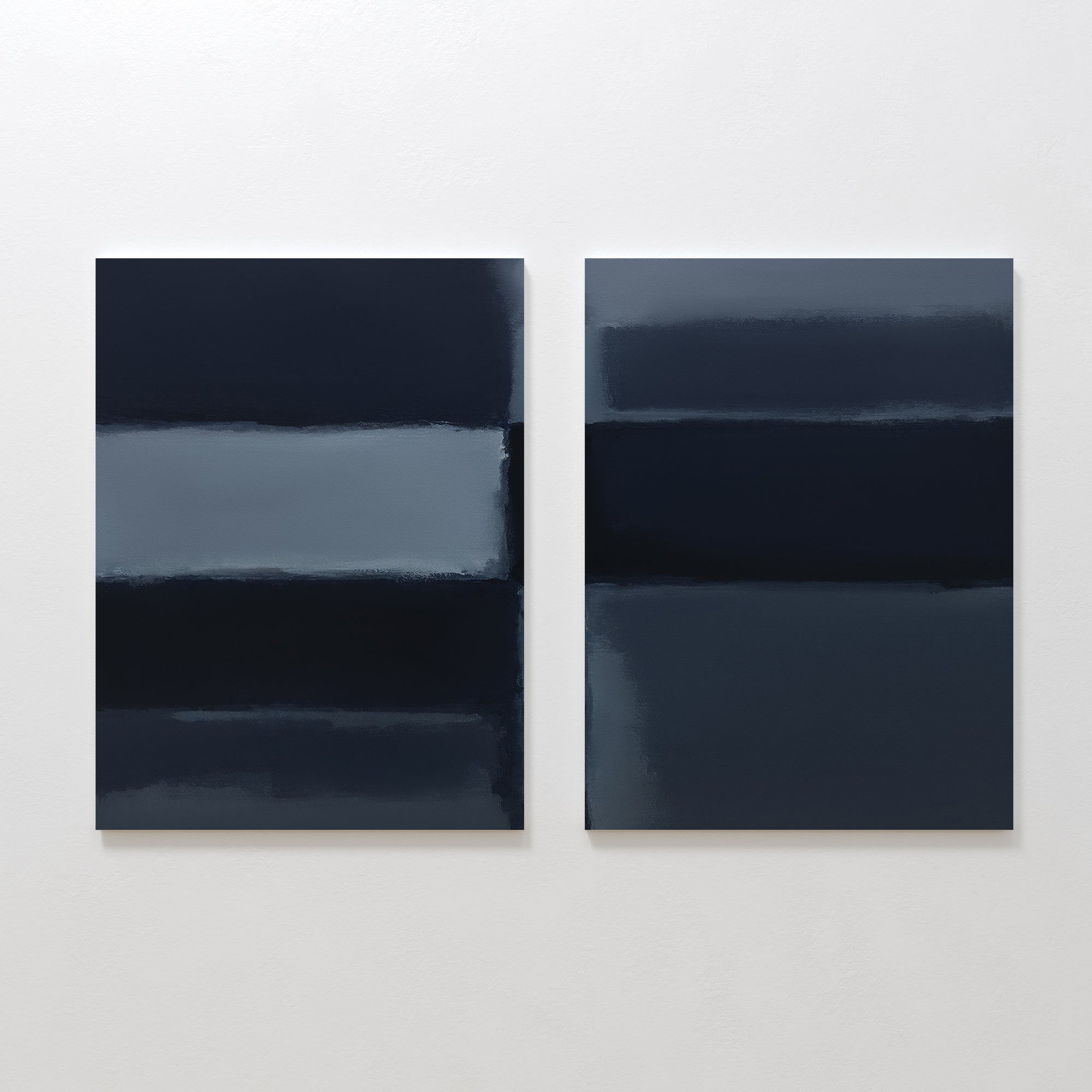 The "Charcoal Blocks - Set Of 2" features two abstract paintings with horizontal bands of dark blue, gray, and black on a white wall—modern wall art with soft, blended edges for a striking visual effect.