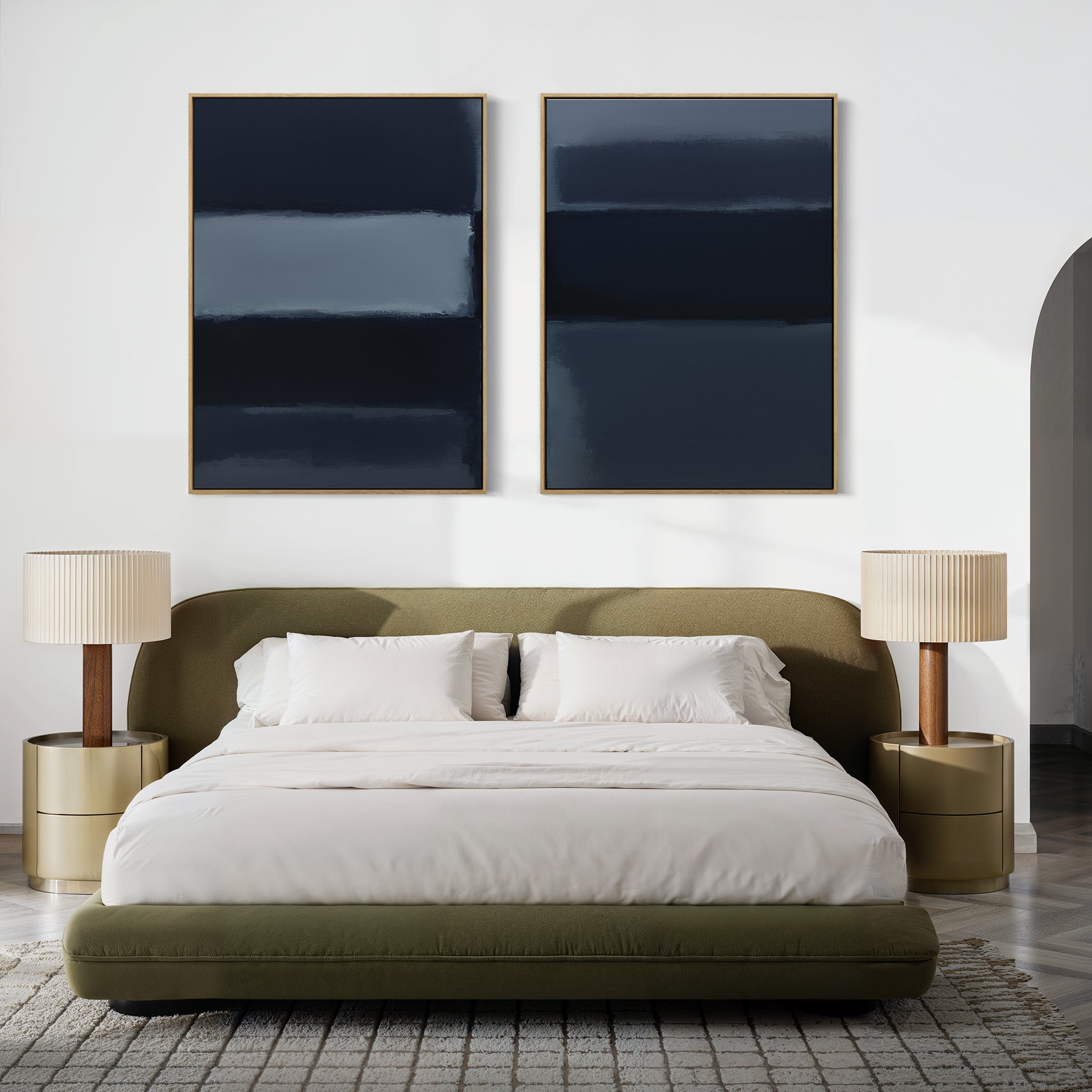 A modern bedroom features a low olive-green bed with white bedding, two round beige nightstands, a neutral area rug, and striking wall art—Charcoal Blocks - Set Of 2 large abstract paintings above the bed.