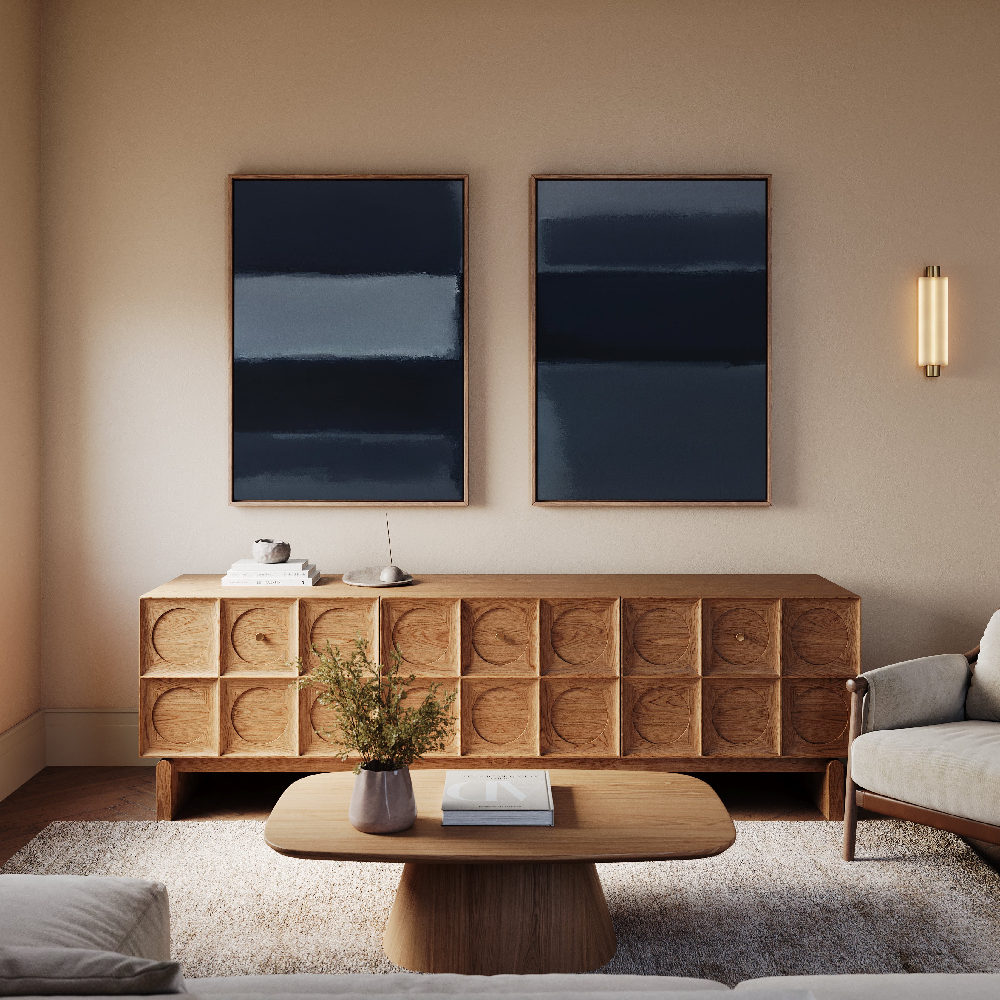 A modern living room featuring the Charcoal Blocks - Set Of 2 as a wooden coffee table, with a textured sideboard, two abstract blue paintings, modern wall art, a cozy armchair, soft rug, and a wall-mounted light fixture.
