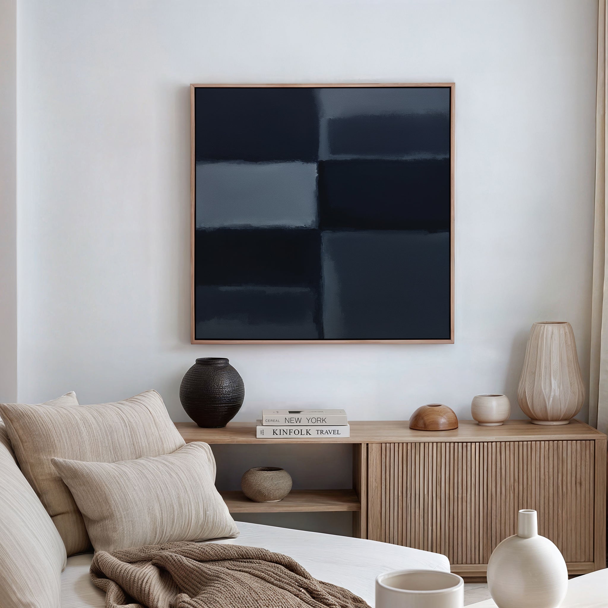 A modern living room with a beige sofa, neutral pillows, a wooden sideboard adorned with vases and books, featuring the Charcoal Blocks Canvas Art - Square as a striking minimalist accent.