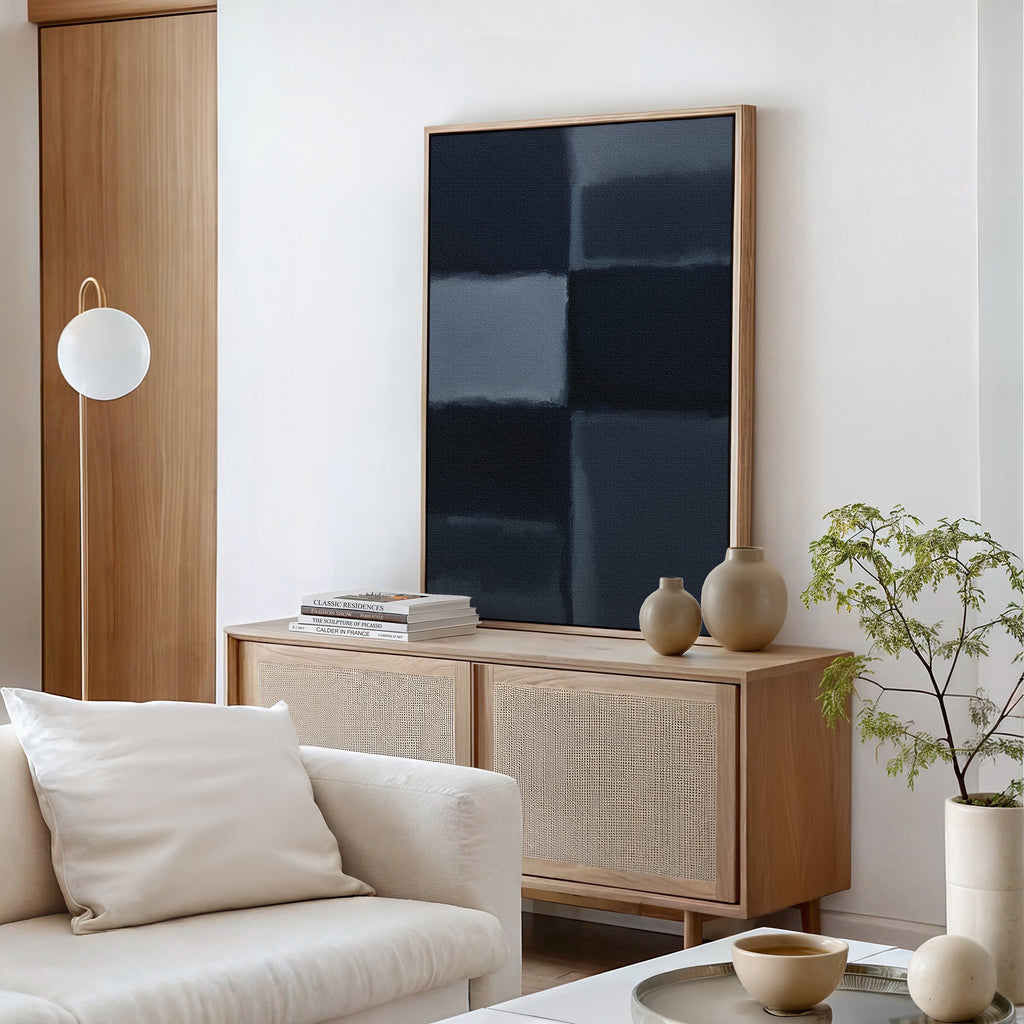 A modern living room features a light wood sideboard, neutral vases, stacked books, potted plant, white globe lamp, beige sofa with a white pillow, and Charcoal Blocks Canvas Art - Vertical for perfect modern home decor.