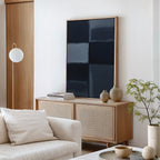 A modern living room features a light wood sideboard, neutral vases, stacked books, potted plant, white globe lamp, beige sofa with a white pillow, and Charcoal Blocks Canvas Art - Vertical for perfect modern home decor.