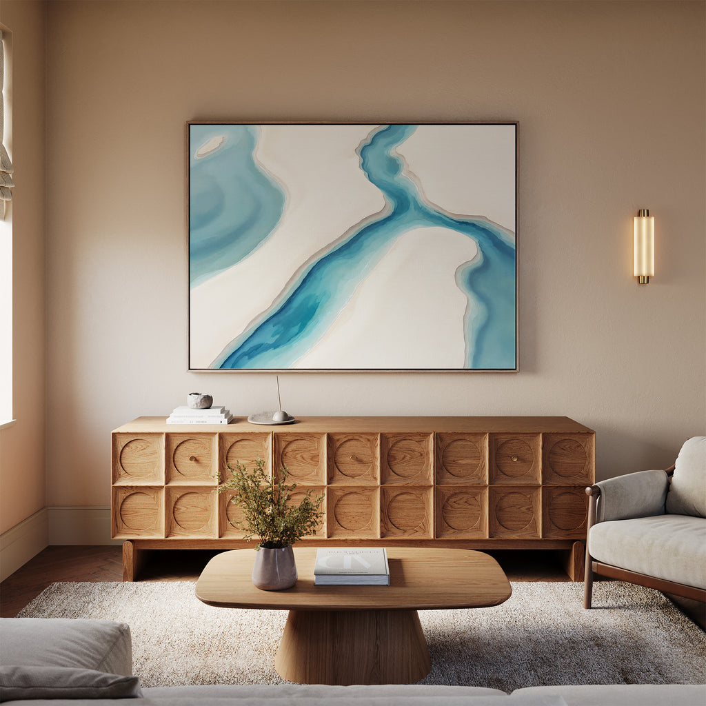 A modern living room with a light wood sideboard, beige sofa, wooden coffee table, vase with flowers, and serene wall art—Coastal Dreams Canvas Art - Horizontal—in blue and white above the sideboard.