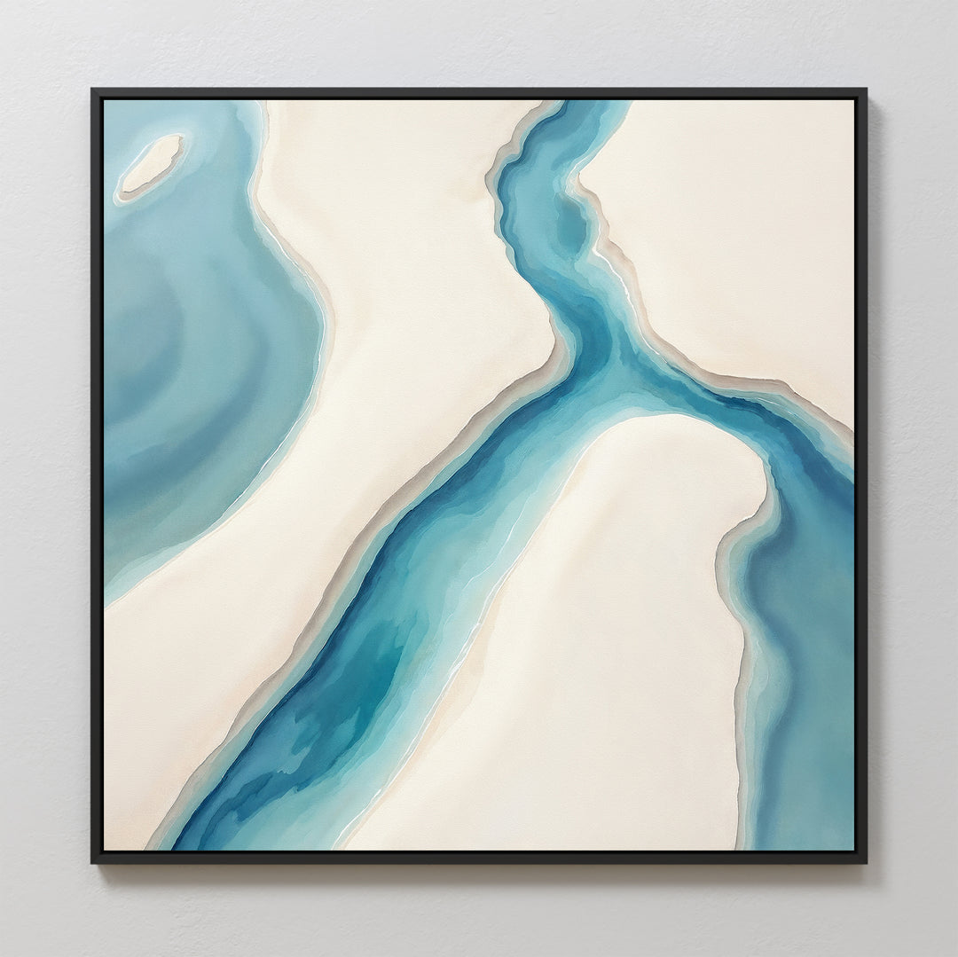 The “Coastal Dreams Canvas Art - Square” features an abstract aerial view of a winding blue river between beige and white sandbanks. This serene piece comes framed in black and is displayed on a light-colored wall.