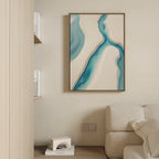 A modern living room corner with a beige sofa, built-in shelves, and serene decor featuring the Coastal Dreams Canvas Art - Vertical, an abstract print with blue and beige shapes hanging on a light wall above a small white sculpture.